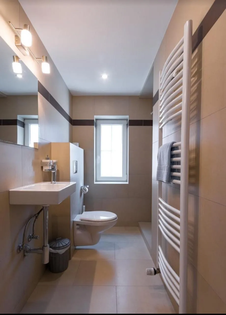 Helles Badezimmer mit Waschbecken, Fenster und Handtuchheizung